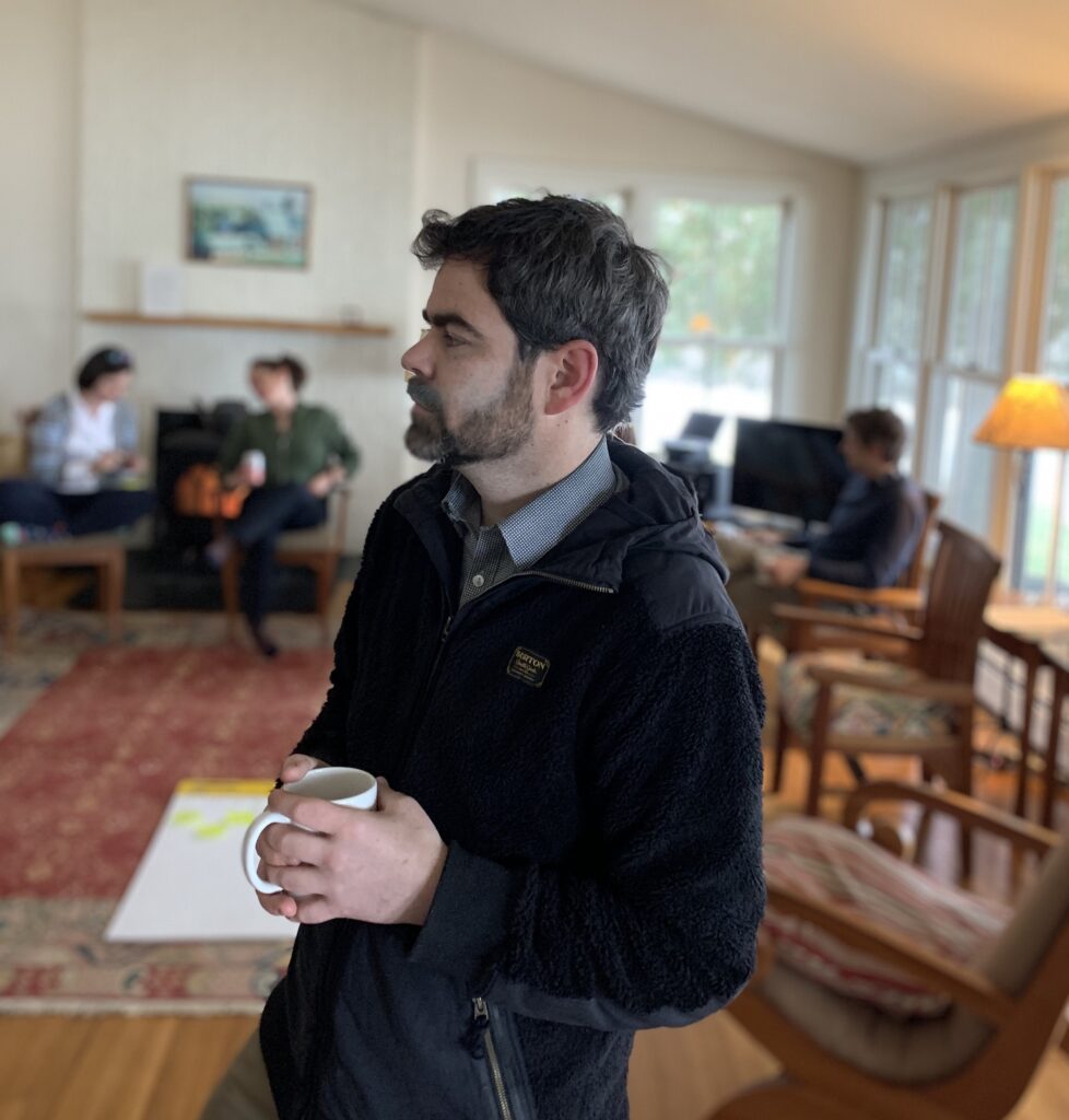Photo: Mike McRaith holds a cup of coffee in reflection at The Dark Side retreat for educational leaders
