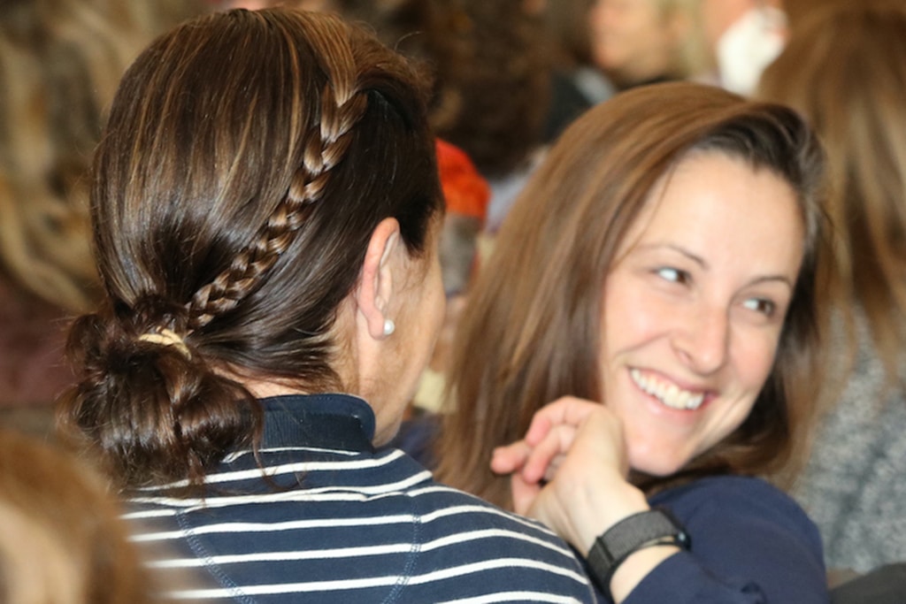 Close-up photo of conference attendee as she looks behind her with a smile, connecting with another educator in the audience